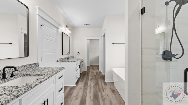 bathroom with hardwood / wood-style floors, vanity, and shower with separate bathtub