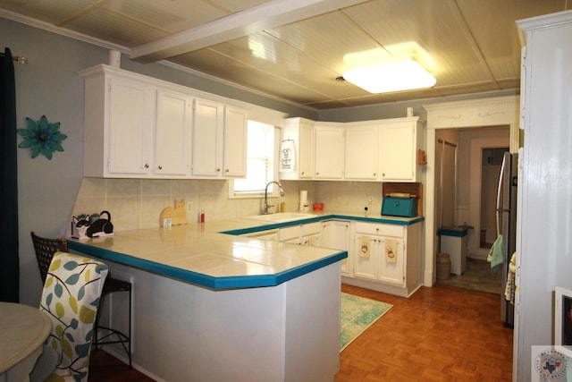 kitchen featuring tile counters, white cabinets, sink, kitchen peninsula, and parquet floors