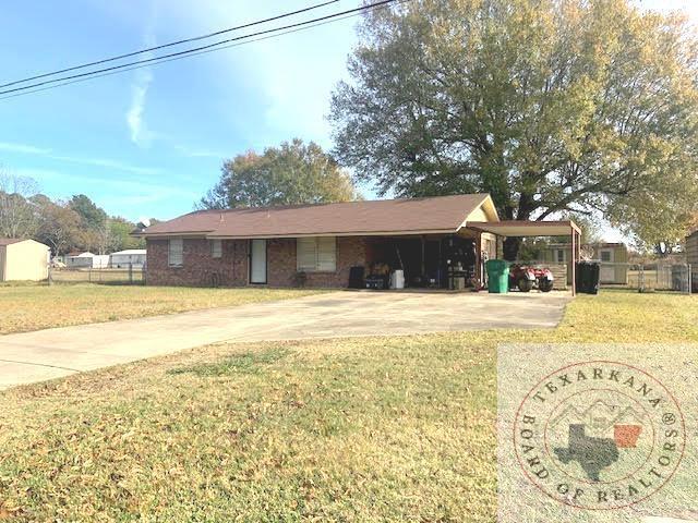 ranch-style house with a front yard and a carport