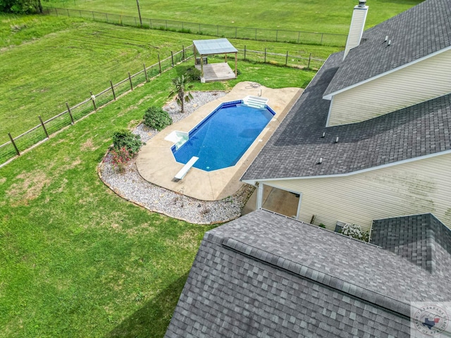 view of swimming pool with a patio area, a yard, a rural view, and a diving board