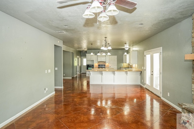 kitchen featuring kitchen peninsula, a kitchen breakfast bar, decorative light fixtures, white cabinets, and black oven