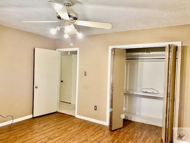 unfurnished bedroom featuring a textured ceiling, light hardwood / wood-style flooring, a closet, and ceiling fan