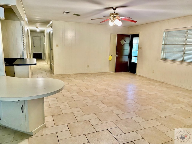 empty room with ceiling fan and wooden walls