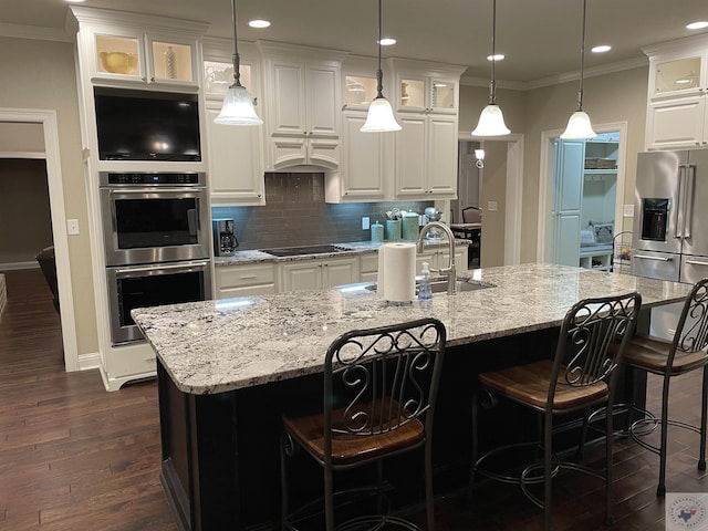 kitchen featuring white cabinets, ornamental molding, appliances with stainless steel finishes, backsplash, and dark wood finished floors