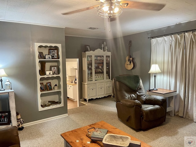 sitting room featuring carpet floors, ornamental molding, and ceiling fan