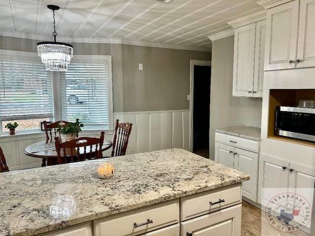 kitchen featuring pendant lighting, white cabinetry, light stone counters, and a notable chandelier