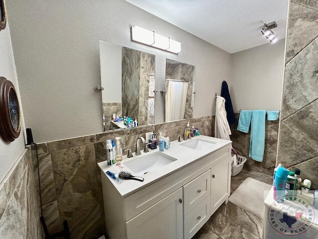 bathroom with vanity, a shower with shower curtain, tile walls, and a textured ceiling