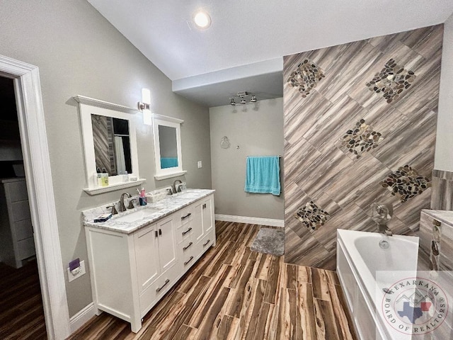 bathroom with hardwood / wood-style flooring, vanity, a bathing tub, and vaulted ceiling