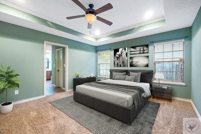 carpeted bedroom featuring ceiling fan, a tray ceiling, and ornamental molding