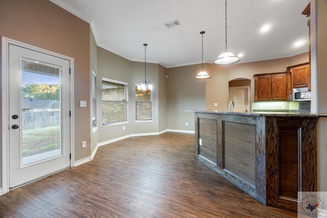 kitchen with crown molding, pendant lighting, light stone countertops, and dark hardwood / wood-style flooring