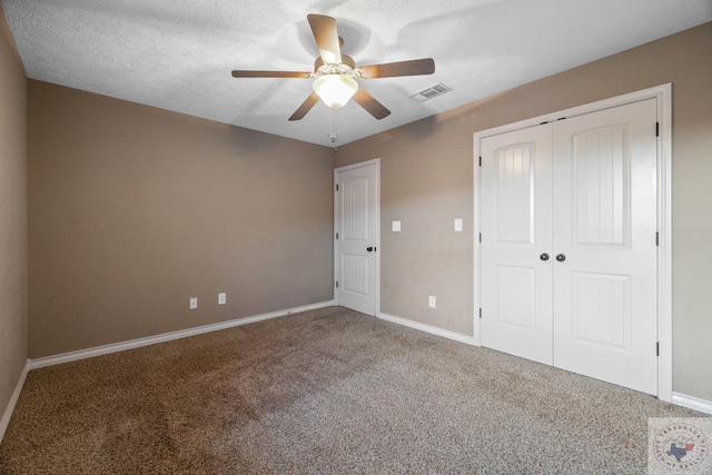 unfurnished bedroom with a closet, ceiling fan, carpet, and a textured ceiling