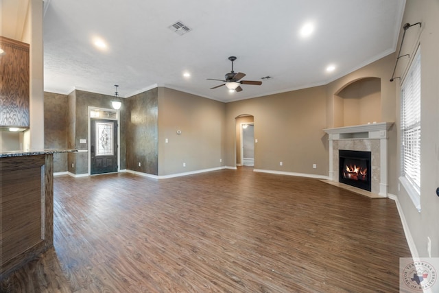 unfurnished living room featuring ceiling fan, dark wood-type flooring, ornamental molding, and a tiled fireplace