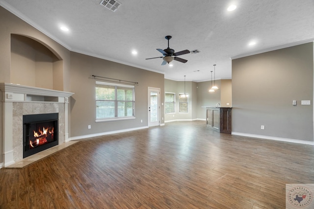 unfurnished living room featuring crown molding, hardwood / wood-style flooring, a textured ceiling, and a fireplace