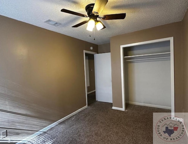 unfurnished bedroom featuring dark colored carpet, a textured ceiling, a closet, and ceiling fan