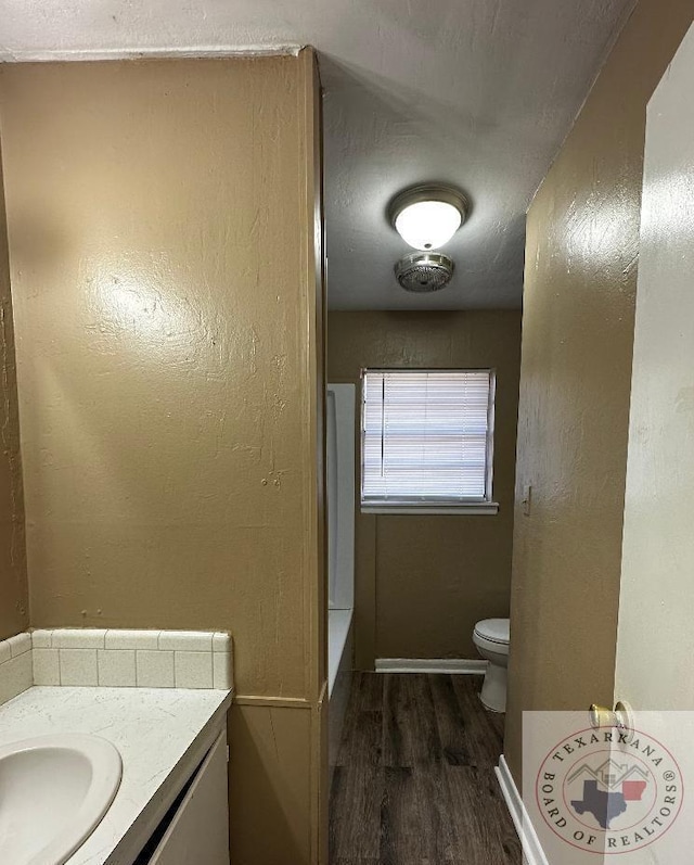 bathroom with a tub, hardwood / wood-style flooring, toilet, and vanity