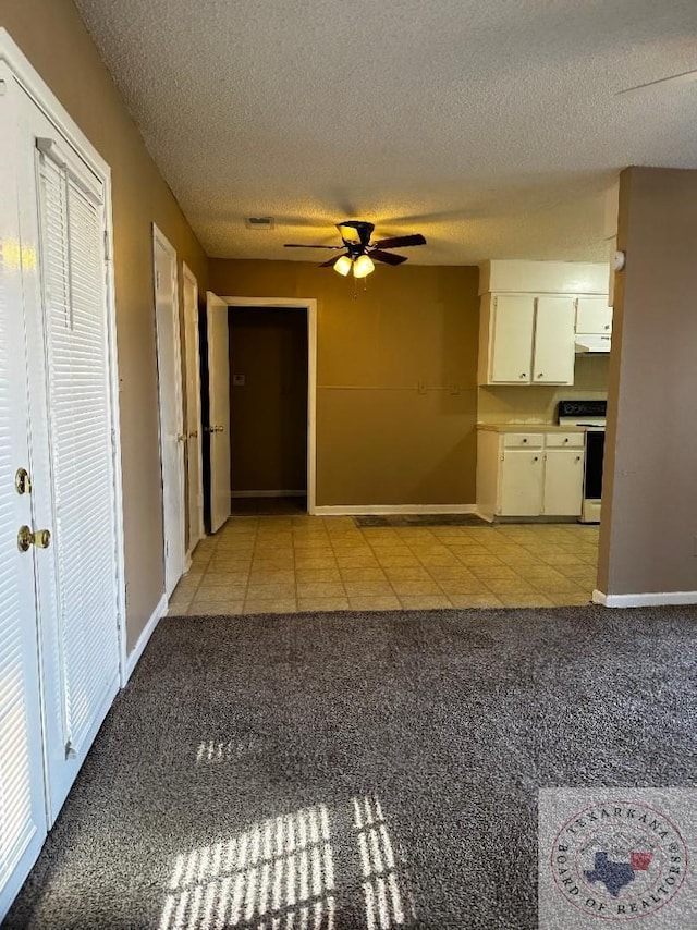 hallway with a textured ceiling and light carpet