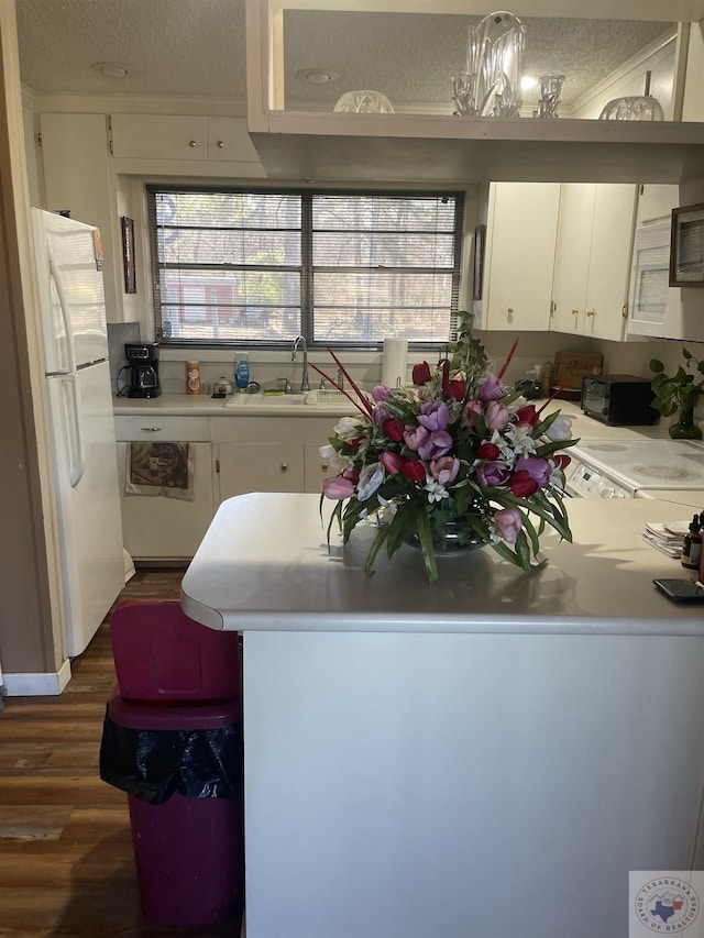 kitchen featuring white cabinetry, sink, kitchen peninsula, pendant lighting, and white refrigerator