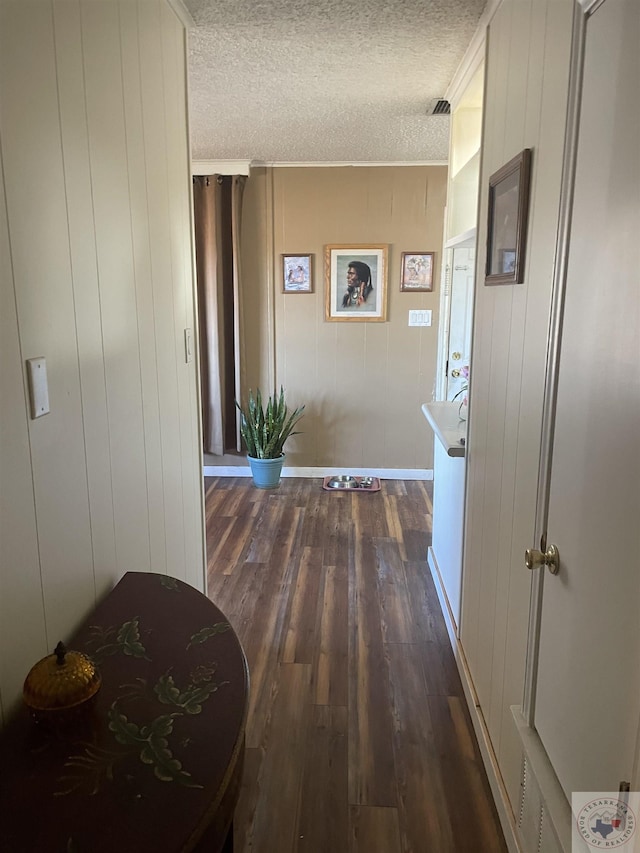 hall featuring wood walls, dark hardwood / wood-style floors, and a textured ceiling