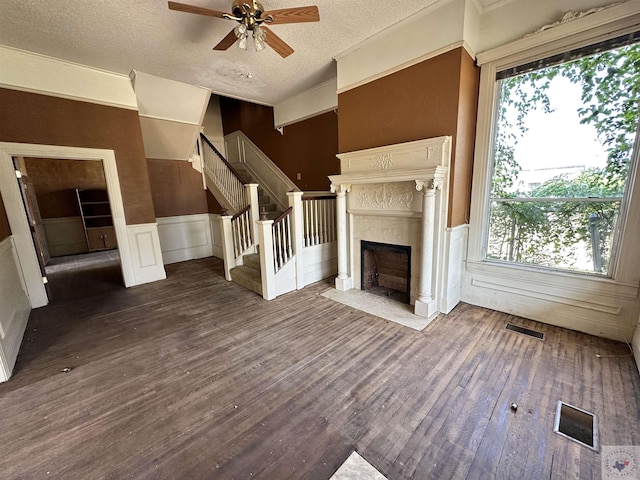 unfurnished living room with ceiling fan, a textured ceiling, and dark hardwood / wood-style flooring