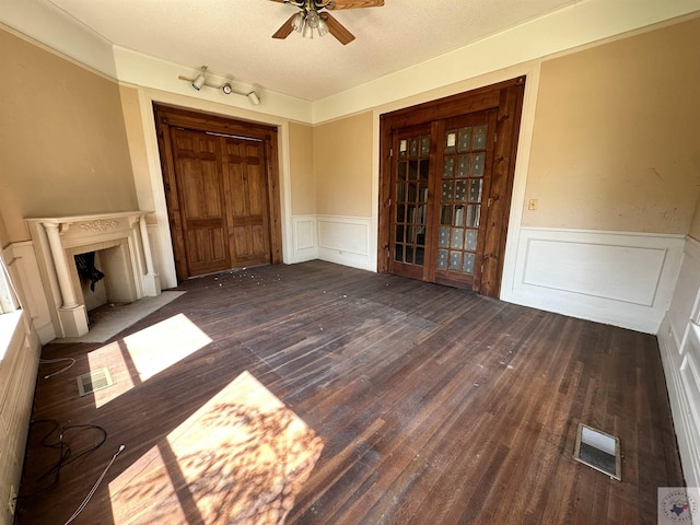 unfurnished living room featuring dark wood-type flooring, a textured ceiling, and ceiling fan