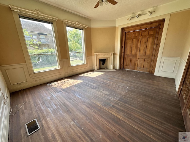 unfurnished living room featuring ceiling fan, dark wood-type flooring, and a textured ceiling