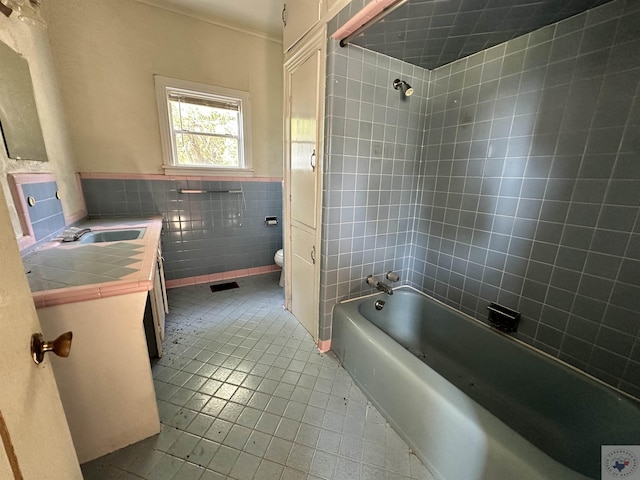 full bathroom with vanity, toilet, tile walls, and tiled shower / bath