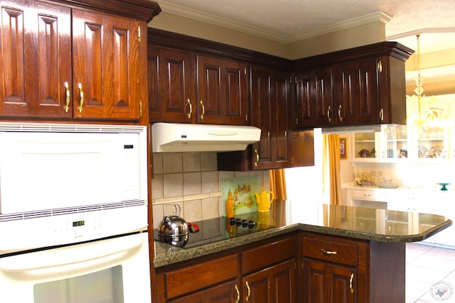 kitchen featuring white appliances, dark stone counters, backsplash, ornamental molding, and light tile patterned floors