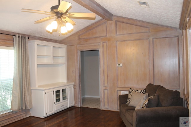 living room featuring a textured ceiling, built in shelves, vaulted ceiling with beams, ceiling fan, and dark hardwood / wood-style floors