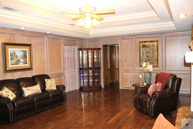 living room with dark hardwood / wood-style flooring, ornamental molding, a raised ceiling, and ceiling fan