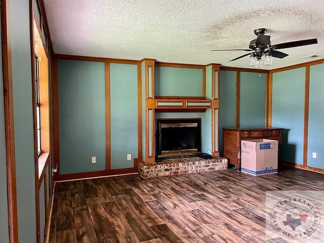 unfurnished living room featuring ceiling fan, a textured ceiling, a brick fireplace, and dark hardwood / wood-style flooring