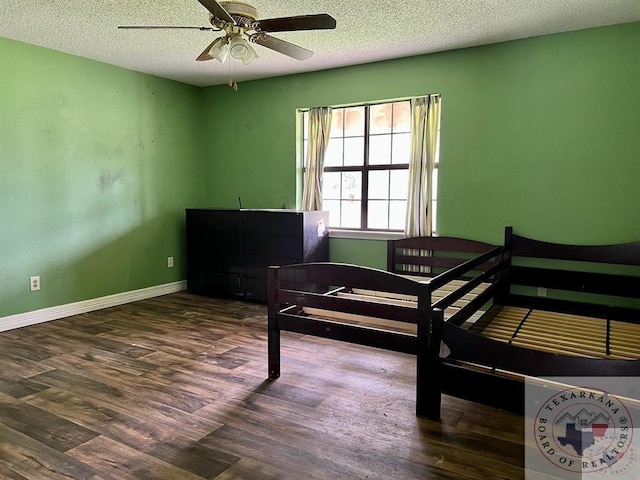 bedroom with ceiling fan, dark hardwood / wood-style floors, and a textured ceiling