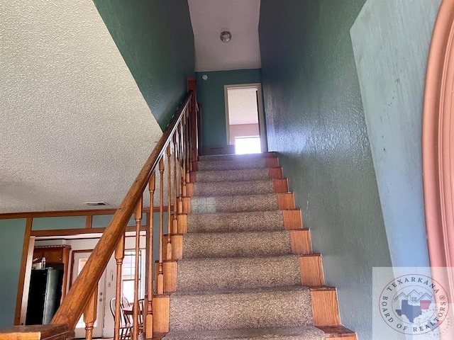 stairs featuring a textured ceiling