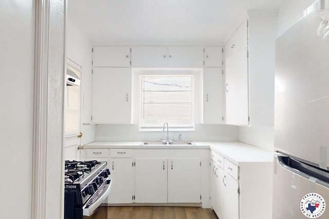 2451 Oaklawn Dr, Texarkana, TX 75501 - kitchen with light wood-style flooring, a sink, freestanding refrigerator, white cabinets, and gas stove