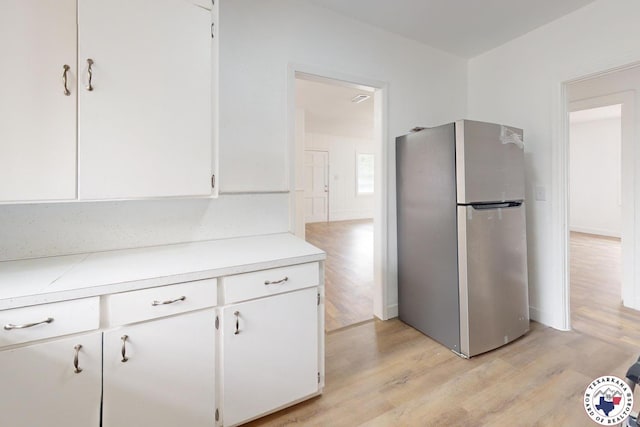 2451 Oaklawn Dr, Texarkana, TX 75501 - kitchen featuring freestanding refrigerator, white cabinetry, light countertops, and light wood finished floors