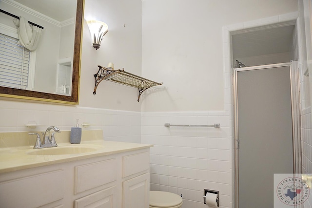 bathroom with a shower with door, vanity, tile walls, toilet, and ornamental molding