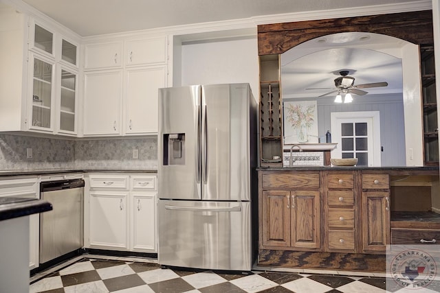 kitchen with ceiling fan, appliances with stainless steel finishes, white cabinetry, ornamental molding, and decorative backsplash