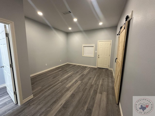 empty room featuring dark hardwood / wood-style floors and a barn door