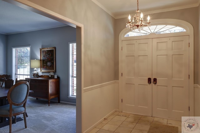 foyer with ornamental molding, plenty of natural light, light tile patterned floors, and an inviting chandelier