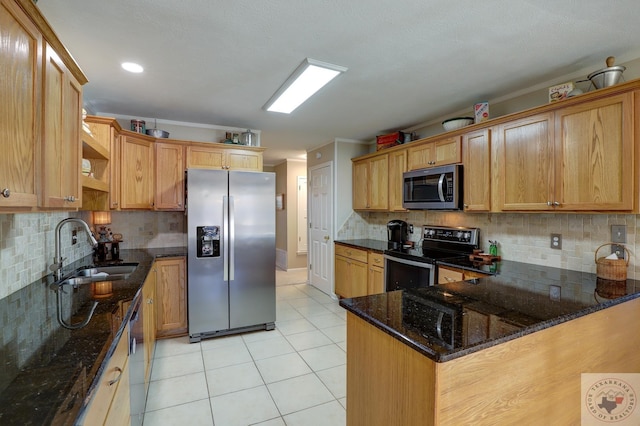 kitchen with appliances with stainless steel finishes, dark stone countertops, decorative backsplash, sink, and light tile patterned floors