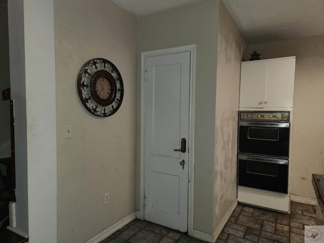 kitchen with white cabinetry, double wall oven, and a textured ceiling