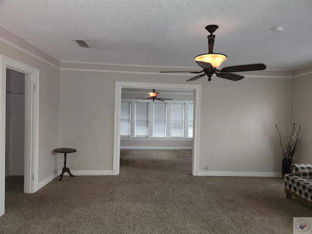 empty room featuring a textured ceiling, carpet floors, and ceiling fan