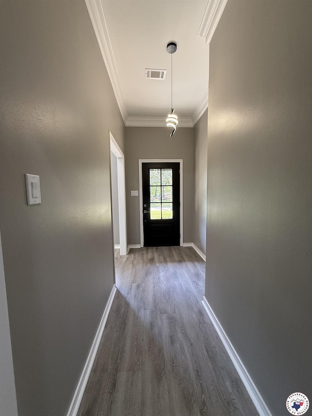 doorway with crown molding, visible vents, baseboards, and dark wood finished floors