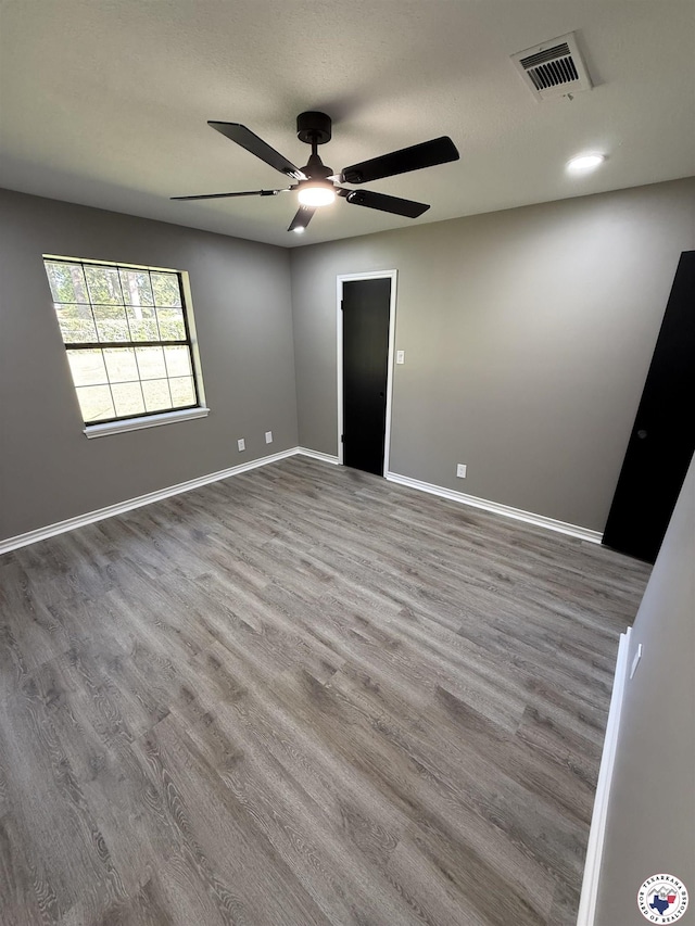 unfurnished bedroom with visible vents, baseboards, a ceiling fan, and wood finished floors