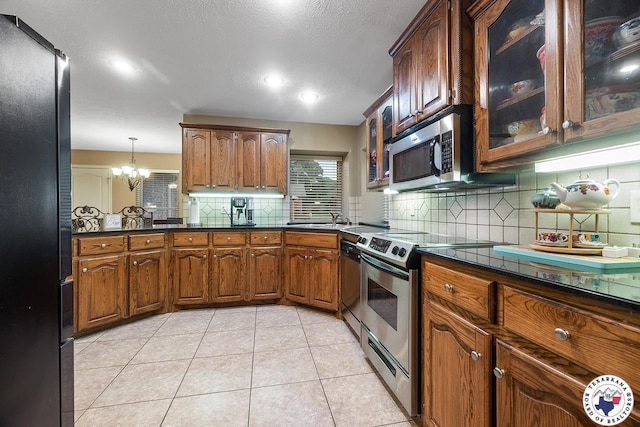 6404 N Park Rd, Texarkana, TX 75503 - kitchen with dark countertops, tasteful backsplash, a notable chandelier, glass insert cabinets, and stainless steel appliances