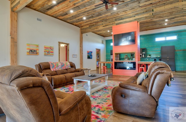 living room featuring light hardwood / wood-style floors, a fireplace, wooden ceiling, a high ceiling, and ceiling fan