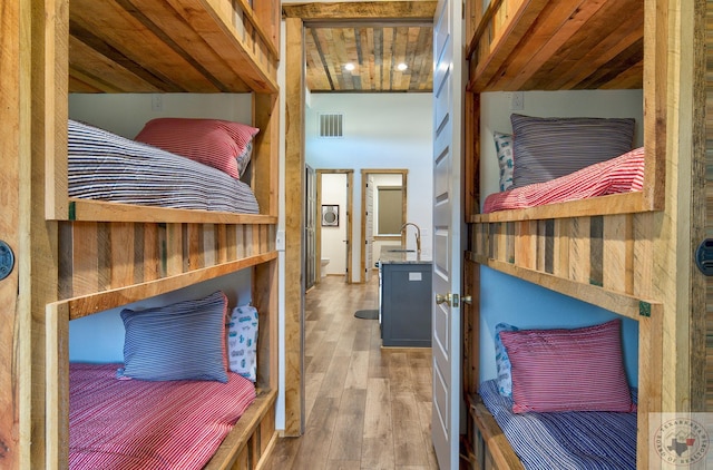 bedroom featuring sink, wood-type flooring, and wood ceiling