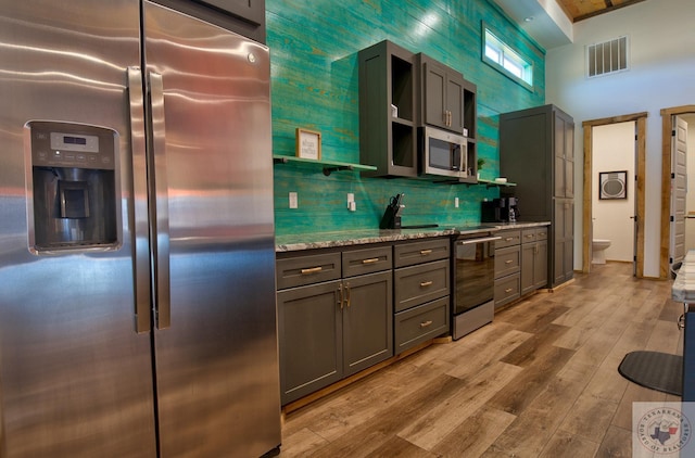 kitchen with light stone counters, light hardwood / wood-style floors, stainless steel appliances, and tasteful backsplash