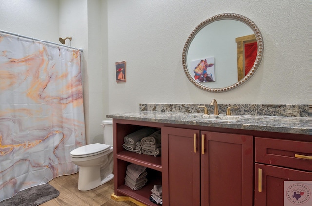 bathroom with hardwood / wood-style floors, toilet, walk in shower, and vanity