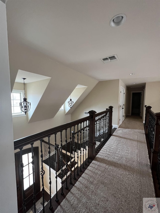 corridor featuring dark carpet, an inviting chandelier, and lofted ceiling