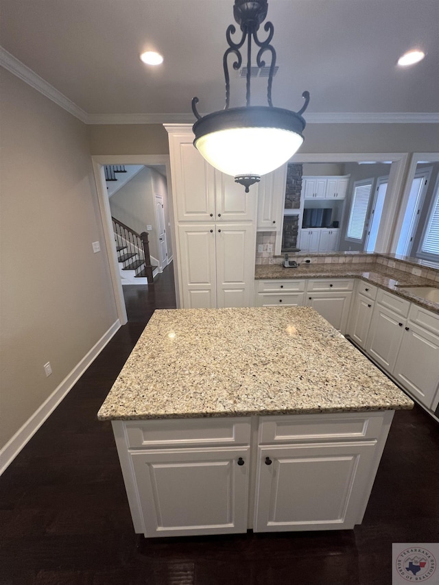 kitchen featuring white cabinets, crown molding, and light stone countertops